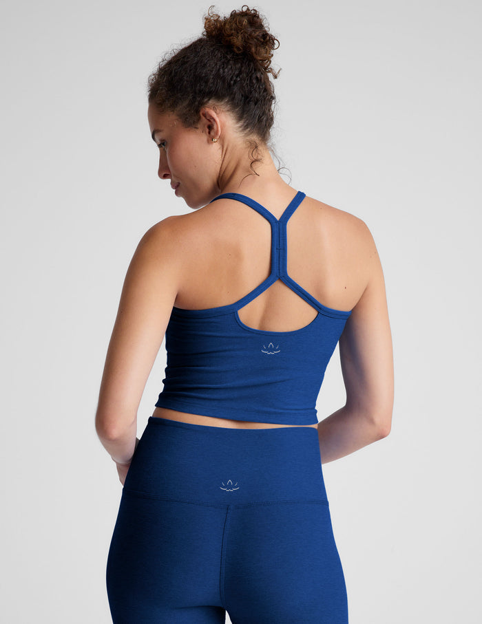 Woman wearing a blue racerback cropped tank against a plain background.