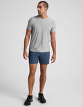 Blue marled Spacedye Unlimited Men's Short with a 7 inch inseam and relaxed fit, worn by a man with a gray t-shirt.