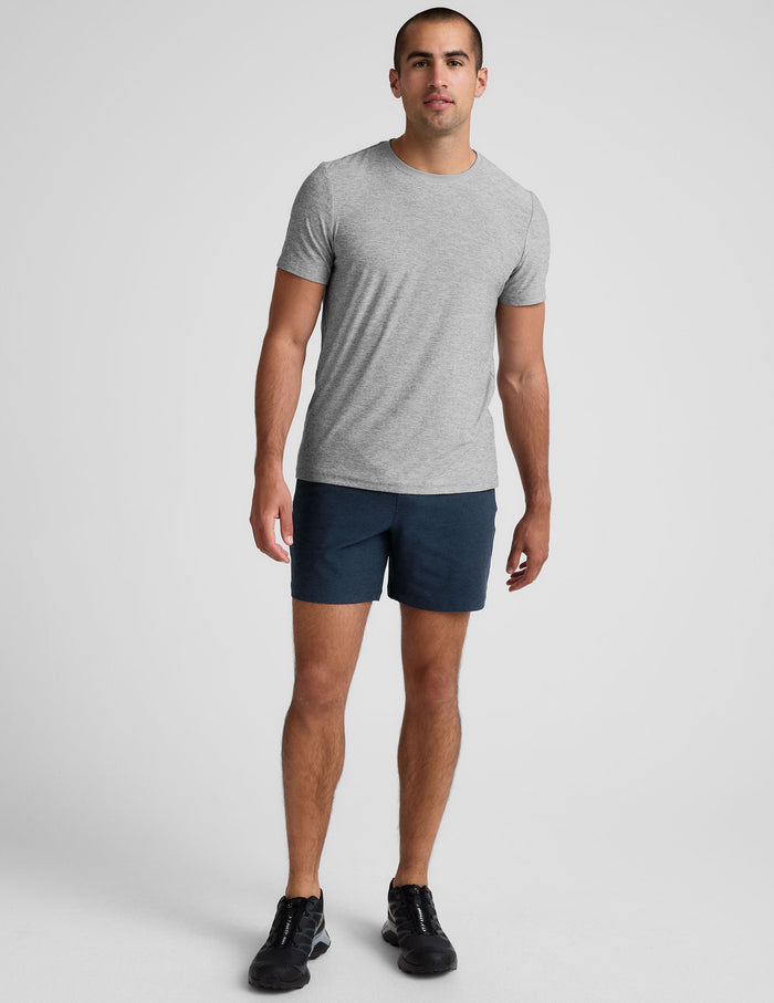 Man wears navy Spacedye Unlimited Men's Shorts with a 7" inseam, paired with a grey t-shirt and black sneakers.