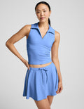Woman wearing a blue sleeveless top and skirt set on a gray background.