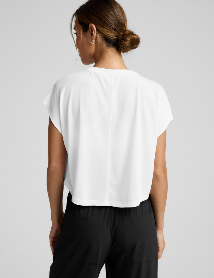 Woman wearing a white top and black pants on a gray background.